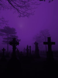 a purple background with crosses and tombstones in the foreground